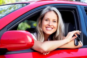 Happy young smiling woman with a car key. New automobile.